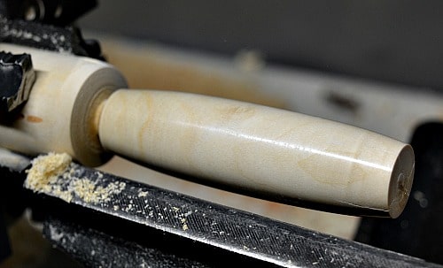 Fidget Stick held in a multi-jawed chuck, sanded and finished ready to be parted from the lathe